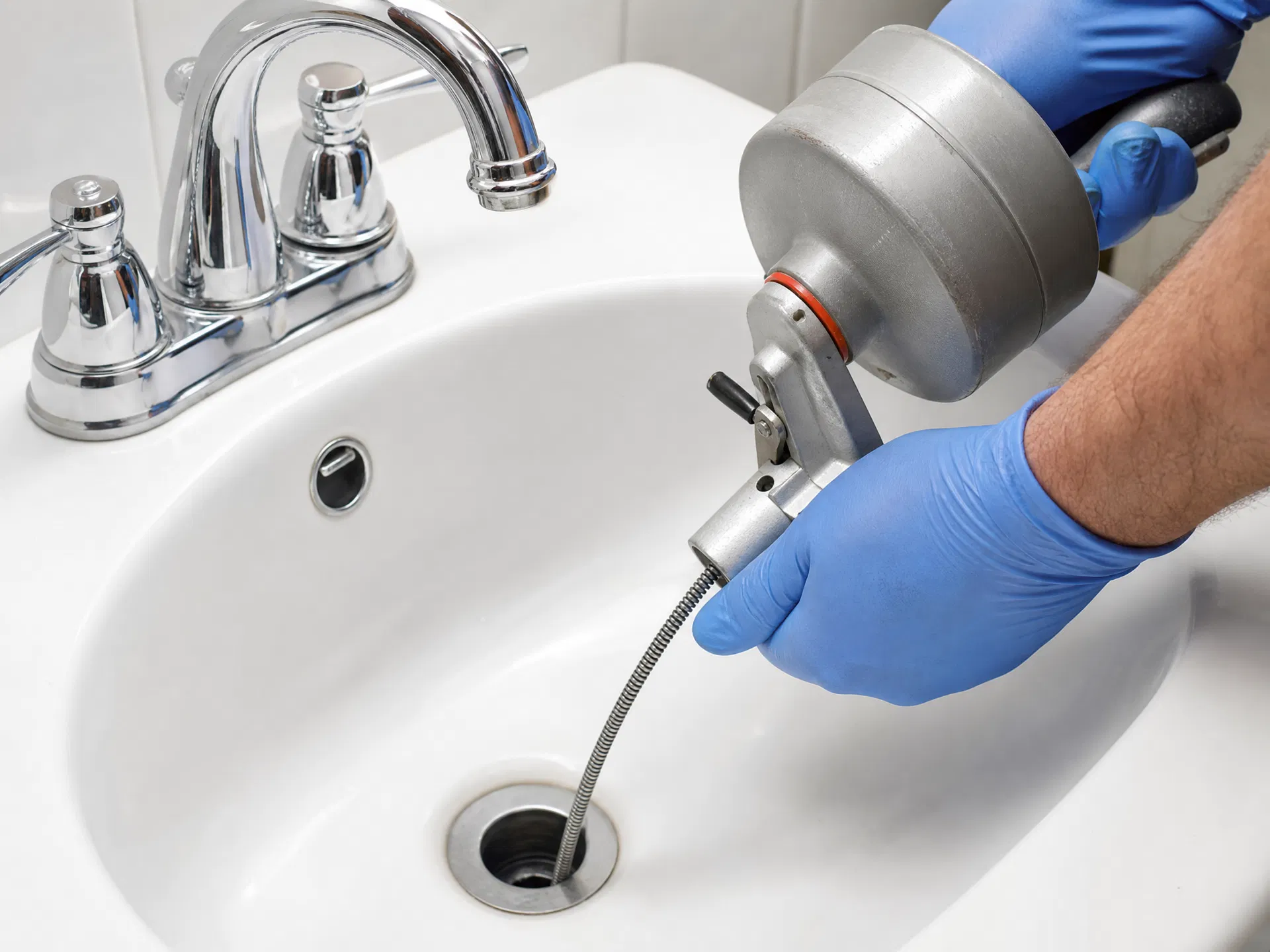 Plumber clearing a clogged drain with a drain snake