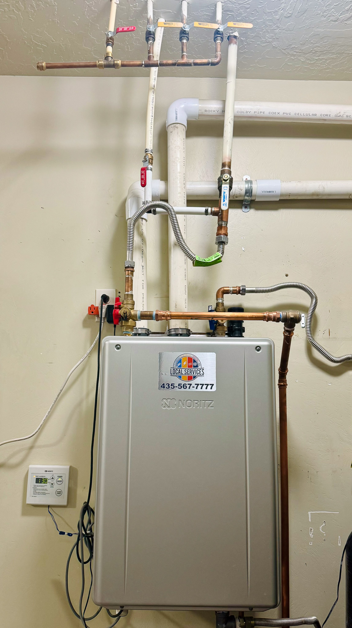 Noritz tankless water heater wall-mounted installation with Local Services Inc. sticker